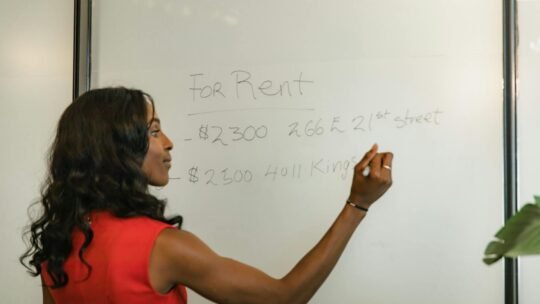 Professional woman writing real estate prices on a whiteboard for rental properties.