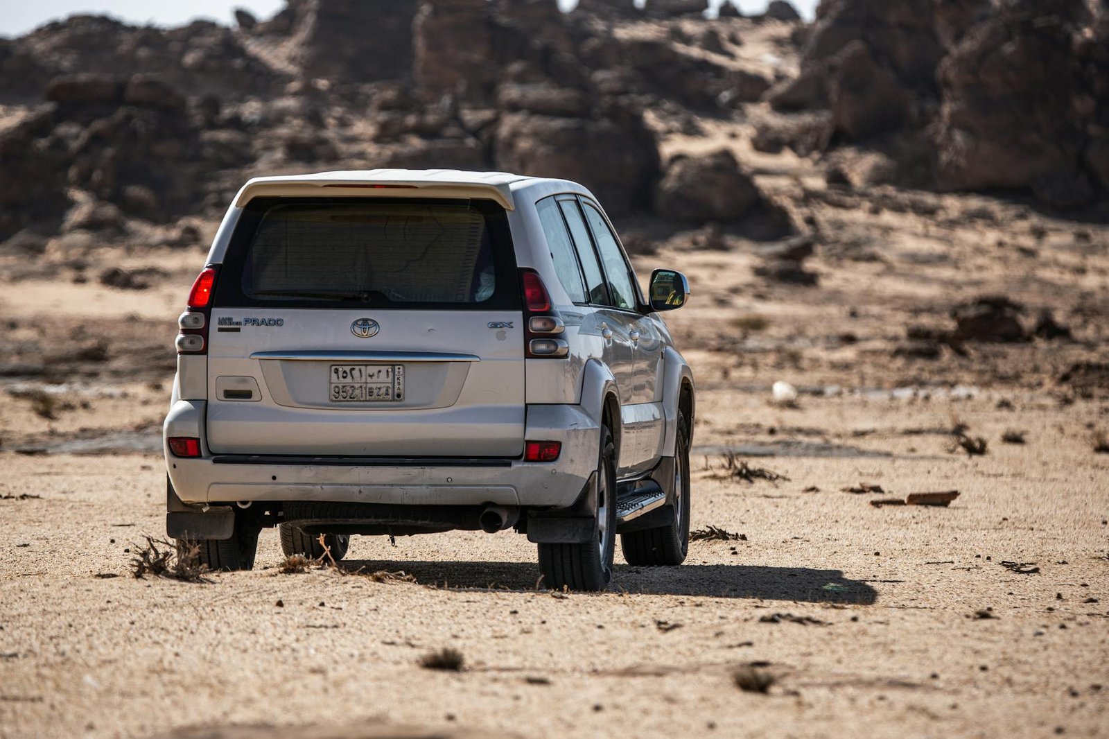 A Toyota Prado SUV parked in a rugged desert landscape, showcasing adventure and off-road capability.
