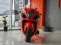 Close-up of a red sports motorcycle parked indoors in a showroom setting.