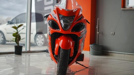 Close-up of a red sports motorcycle parked indoors in a showroom setting.