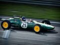 A green vintage Formula 1 car with number 25 speeds around a racetrack, showcasing classic racing heritage.