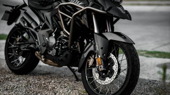 Detailed view of a black motorcycle parked on a gravel road.