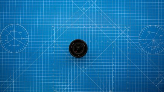 Top view of a camera lens on a blue geometric grid mat, showcasing photography equipment.