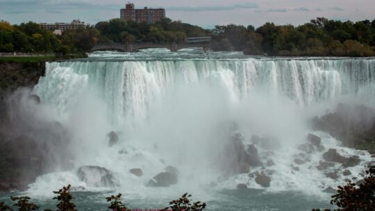 Majestic view of Niagara Falls cascading into the river below on a calm day.