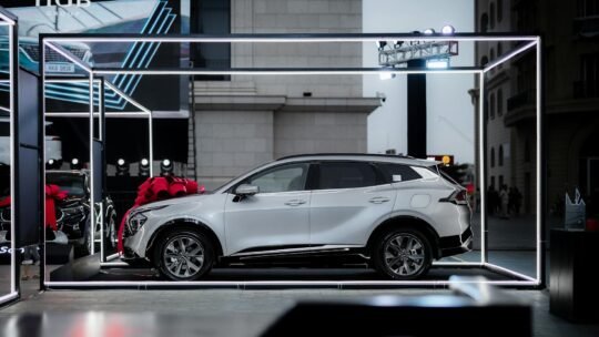 A sleek modern SUV showcased at an outdoor car exhibition with urban architecture.