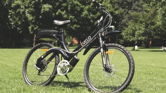 A stylish electric bike parked on lush green grass under the sunny sky.