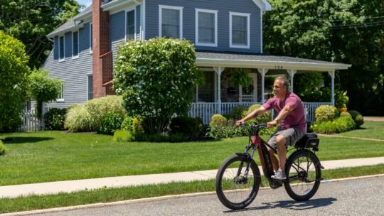 A man enjoys a sunny ride on his electric bike in a suburban neighborhood.