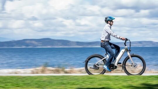 A man rides an electric bicycle along a seaside path, embracing outdoor adventure.