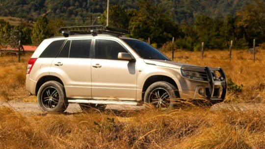 A Suzuki Grand Vitara parked in a rural landscape scene, offering an adventurous vibe.