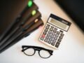 Calculator with glasses and folders on an office desk. Perfect for finance and accounting themes.
