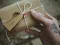 Close-up of a hand holding a thank you gift adorned with a rose tattoo, conveying a personal touch.