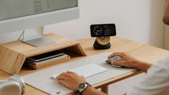 A clean and modern desk setup featuring a computer, clock, and accessories in a home office.