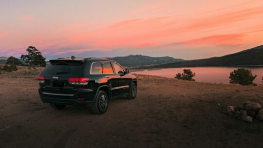 Black Jeep Grand Cherokee overlooking a scenic lake during sunset in Colorado Springs.