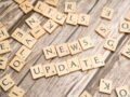 Scrabble tiles spelling 'News Update' on a wooden background, ideal for media and communication concepts.