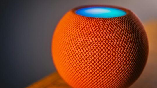 Close-up of an orange smart speaker with a glowing blue light, showcasing modern technology.