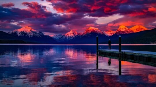 Stunning sunset over a serene lake with colorful sky and majestic mountains.