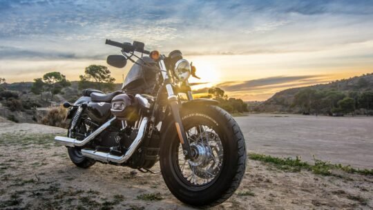 A Harley Davidson motorcycle parked outdoors against a stunning sunset sky, perfect for adventure and travel imagery.