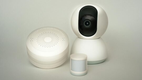 Modern smart home devices including a camera and sensors on a neutral background.