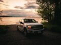 Scenic view of a Ford F-150 truck by a lakeshore in Quebec City at sunset, showcasing the beauty of rural Canada.