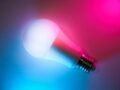 A vibrant LED light bulb with blue and pink neon lighting effects, showcasing smart home technology.