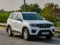 White Mahindra SUV parked on a highway in Deeg, India, surrounded by lush greenery.