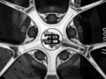 Black and white close-up shot of a Bugatti car rim showing intricate design and luxury branding.