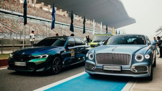 Elegant lineup of luxury cars at a racing event in Greater Noida, India, showcasing Bentley and BMW models.