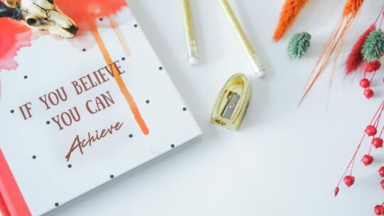 Inspirational flat lay featuring a motivational notebook and stylish stationery on a white background.