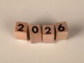 Wooden cubes forming the year 2026 on a neutral background.