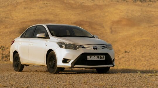A modern white Toyota car parked in a vast desert setting, perfect for automotive imagery.
