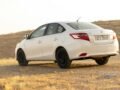 A white Toyota Vios parked in a desert landscape during daylight.