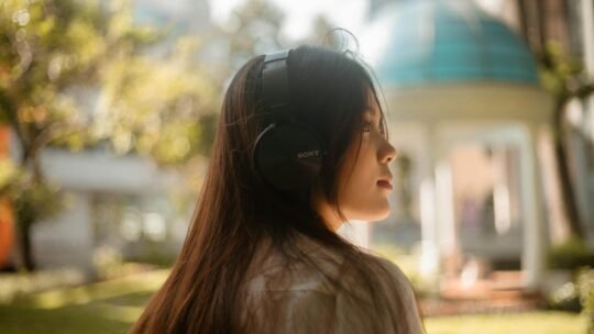 Young woman enjoying music with headphones in a sunny outdoor park.