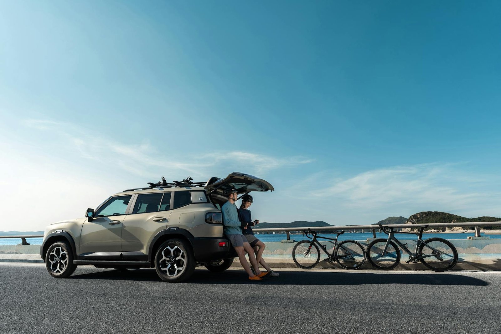 Modern SUV parked on a coastal road with bicycles, ideal for a scenic adventure.
