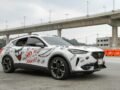 White SUV decorated with Joker-inspired art on a highway under bridge.