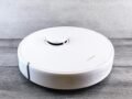 Sleek white robot vacuum cleaner on a wooden floor, perfect for smart home setups.