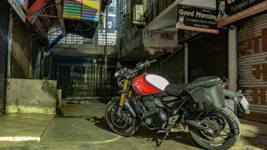 Captivating street view of a red Triumph motorcycle parked in a Delhi alleyway, showcasing urban culture.