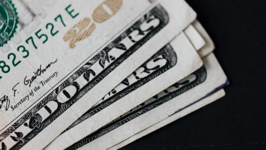 A detailed view of American dollar bills in a close-up shot on a black background, symbolizing finance.