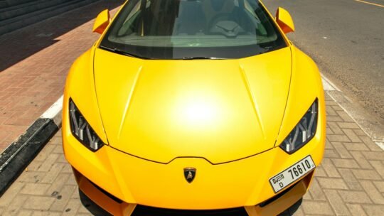 Front view of a parked yellow Lamborghini Aventador on a sunny Dubai street.