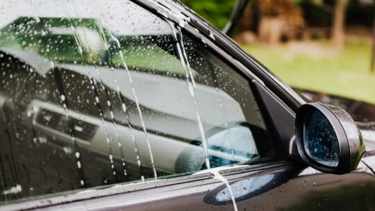 Detail of a car window with soap and water at an outdoor car wash.
