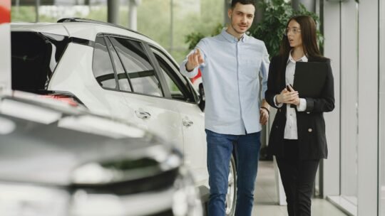 Customer and salesperson discussing a vehicle inside a modern car dealership showroom.