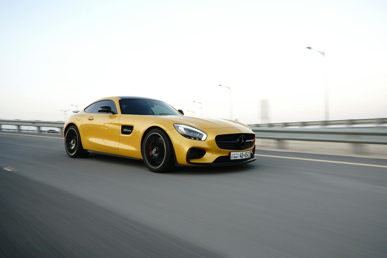 Luxury yellow sports car driving on highway at dusk, showcasing speed and elegance.