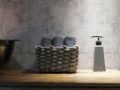 Stylish bathroom setup featuring a woven basket and a contemporary soap dispenser on a wooden countertop.