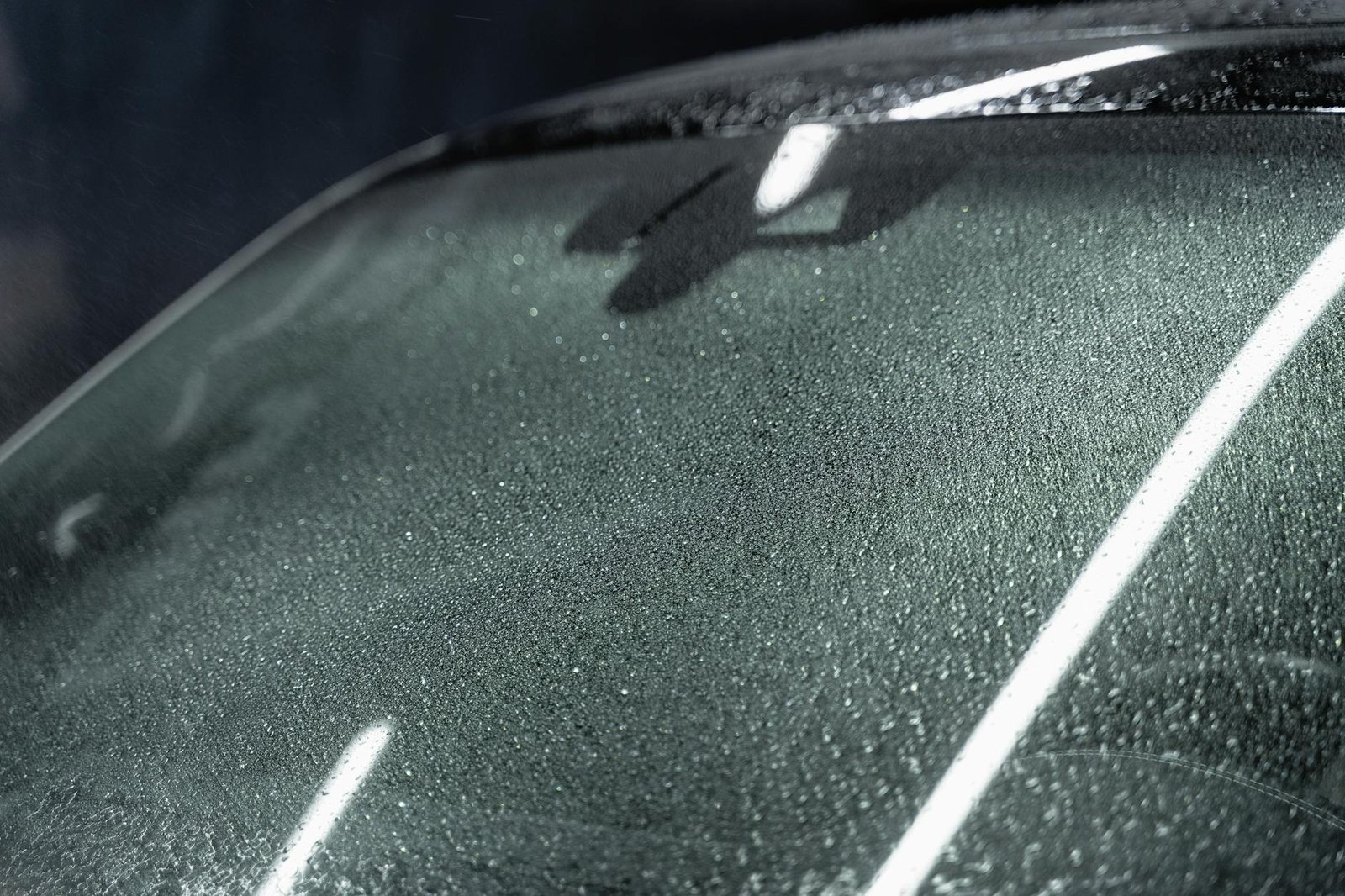 Detailed focus on a car windshield with raindrops, highlighting texture and refraction.