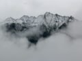 A breathtaking view of snow-covered mountain peaks surrounded by dense fog, creating a mystical landscape.