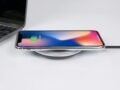 Smartphone wirelessly charging on pad next to a laptop, showcasing modern technology.