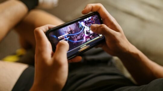 A person playing a mobile video game on a smartphone, focusing on gaming and technology lifestyle.